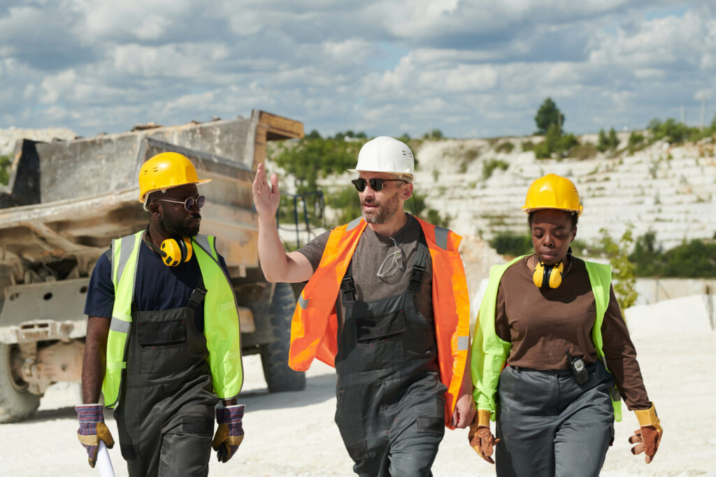 Confident foreman in workwear explaining something to his subordinates