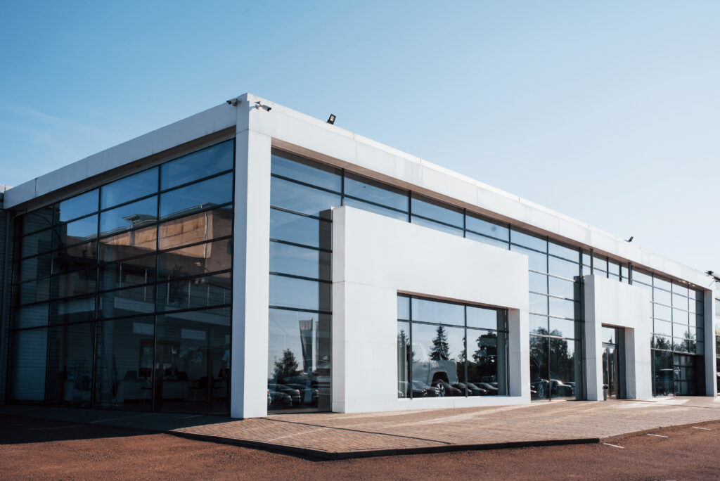 Modern car building. Many vehicles inside. Sunny day with clear sky